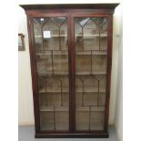 A late Victorian mahogany bookcase with a pair of glazed panelled doors, enclosing five shelves,