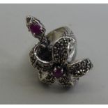 A silver dress ring, set with ruby coloured stones and marcasite, fashioned as a snake and flora