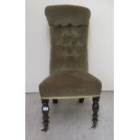 A late Victorian prie dieu, upholstered in a green fabric, raised on turned legs with casters