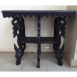 An early/mid 20thC Asian carved hardwood two tier side table with wildlife and C-scroll ornament