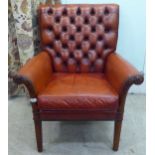 An early/mid 20thC stained beech showwood framed enclosed armchair, part button upholstered in red