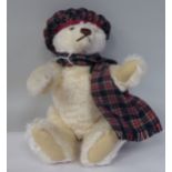 A plush covered Teddy bear wearing tartan with a growler  12"h