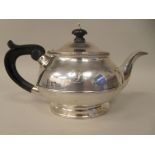 A silver teapot of round bulbous form with a waistband, cast border ornament, a short S-shape spout,