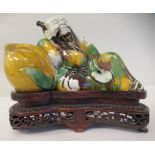 An early 18thC Chinese egg and spinach figure, a reclining sage, on a fitted, carved and pierced