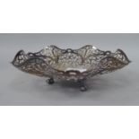 A silver shallow, decoratively pierced, wavy edge basket dish, elevated on cast talon and ball feet
