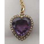 A 9ct gold heart shaped pendant, set with seed pearls around an amethyst coloured stone, on a fine