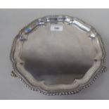 A Georgian style silver waiter with a raised piecrust and gadrooned border, elevated on scrolled