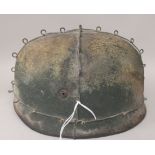 A German World War II military steel helmet, overlaid with wire, the hide liner incorporating