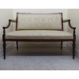 An Edwardian showwood framed and inlaid mahogany salon settee with a straight back and swept, open