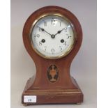 An Edwardian mahogany balloon cased mantel clock with a marquetry motif and string inlaid brass