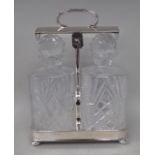 A silver plated tantalus of rectangular, galleried tray design with a central handle and a