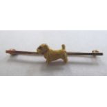A yellow metal bar brooch, mounted with a dog