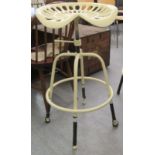 A cream painted cast metal tractor seat design bar stool