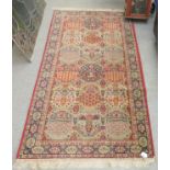 A Persian design rug with floral motifs, on a red ground  36" x 68"