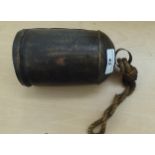 A galvanised metal cow bell, on a rope handle