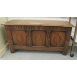An early 20thC oak coffer with straight sides and a hinged lid, over a tri-panelled front, raised on