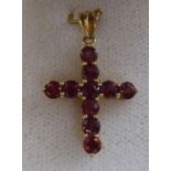 An 18ct gold pendant cross, claw set with ruby coloured stones