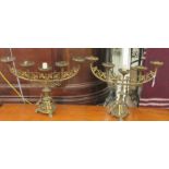 A pair of cast brass five branch candelabra, each decorated with scrolling leaves, surmounted by