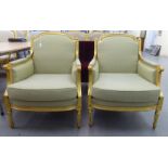 A pair of modern Louis XVI style antique finished gilded showwood framed enclosed arm salon chairs,