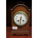 An Edwardian stained mahogany cased bracket clock with inlaid decoration and arched top, on a
