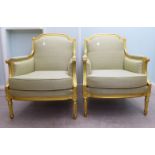 A pair of modern Louis XVI style antique finished gilded showwood framed enclosed arm salon chairs,