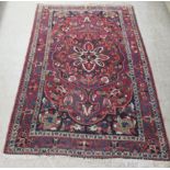 A Seneh rug, decorated with a central star shaped motif, bordered by stylised designs on a multi-