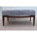 A modern grey/blue hexagonal patterned fabric, cushioned window seat, raised on a mahogany