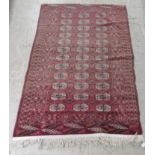 A Bokhara rug, decorated with three columns of twelve guls on a red ground  42" x 68"