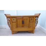 A modern Chinese carved light coloured elm cupboard, the top with pillow flanks, over two doors