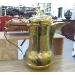 A North African brass floorstanding coffee pot with engraved ornament, a domed cover, angled spout
