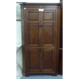 A 20thC oak one piece corner cabinet with two pairs of panelled doors, raised on bracket feet  78"h