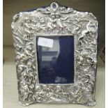 A Victorian style silver mounted photograph frame, decorated in relief with cherubic figures, on