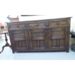 A mid 20thC Jaycee carved and stained oak sideboard with three frieze drawers, over three carved and