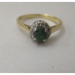 An 18ct gold ring, set with a green stone, surrounded by diamonds