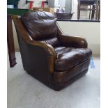 A modern Pegasus soft cushioned, burnished brown hide upholstered enclosed armchair