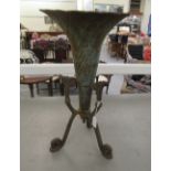 A late 19thC cast iron terrace ornament, fashioned as a trumpet, in a scrolled tripod frame  21"h