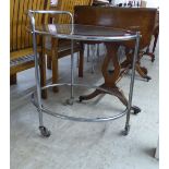 A 1960s/1970s chromium framed tea trolley with a glass top, raised on casters  25"h  26"w