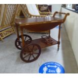 A modern mahogany finished tea trolley with fall flaps, raised on spoked wheels  25"h  30"w