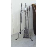 A baronial style polished steel fireside companion, the three imprements on a matching tripod stand