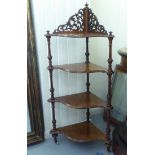 A Victorian walnut four tier serpentine front quadrant whatnot with a fretworked upstand, on