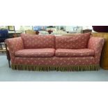 A modern three person settee, upholstered in patterned red fabric and multi-coloured tasselled