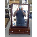 An early 19thC mahogany toilet mirror, the bevelled plate pivoting on angled horns and a three