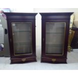 A pair of modern Frenni mahogany finished illuminated hanging display cupboards, each comprising a