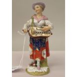 A 19thC Derby porcelain standing figure, a woman wearing a patterned pinafore dress, playing a