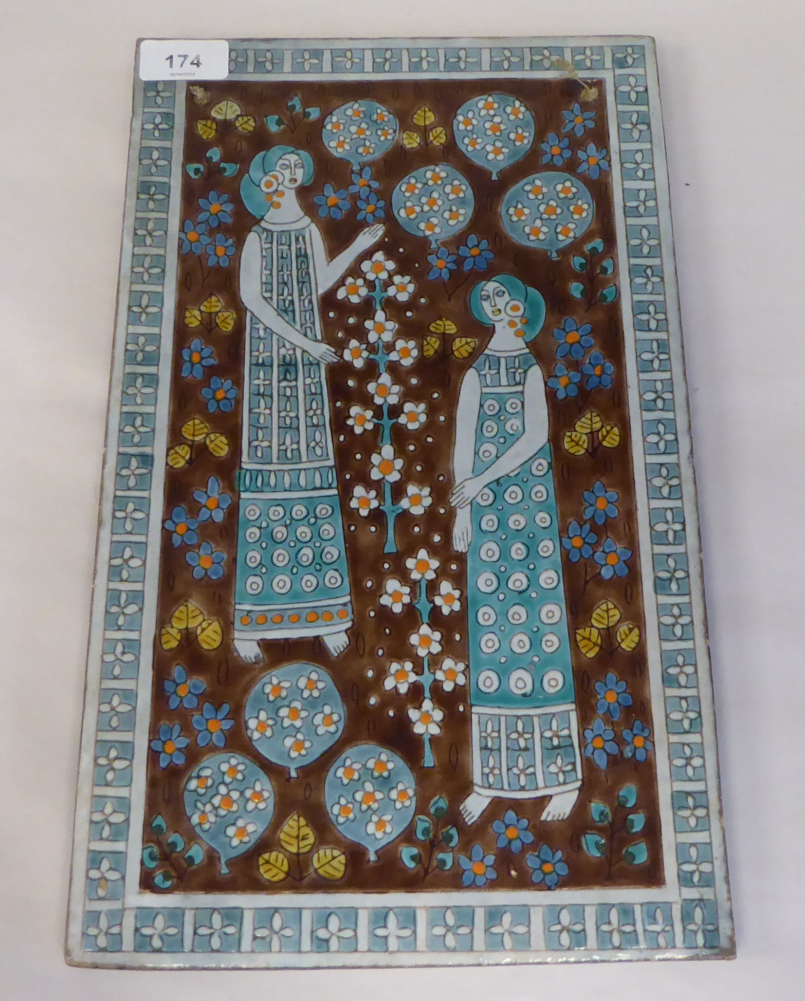 A Szuri Szam art pottery plaque, featuring two standing figures with balloons and flowers  15" x 9"