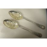 A pair of Edwardian silver berry spoons with embossed and chased bowls, on decoratively cast