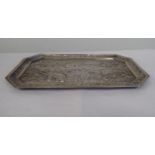 An Indian white metal pin tray of elongated octagonal form, embossed and chased with wild and