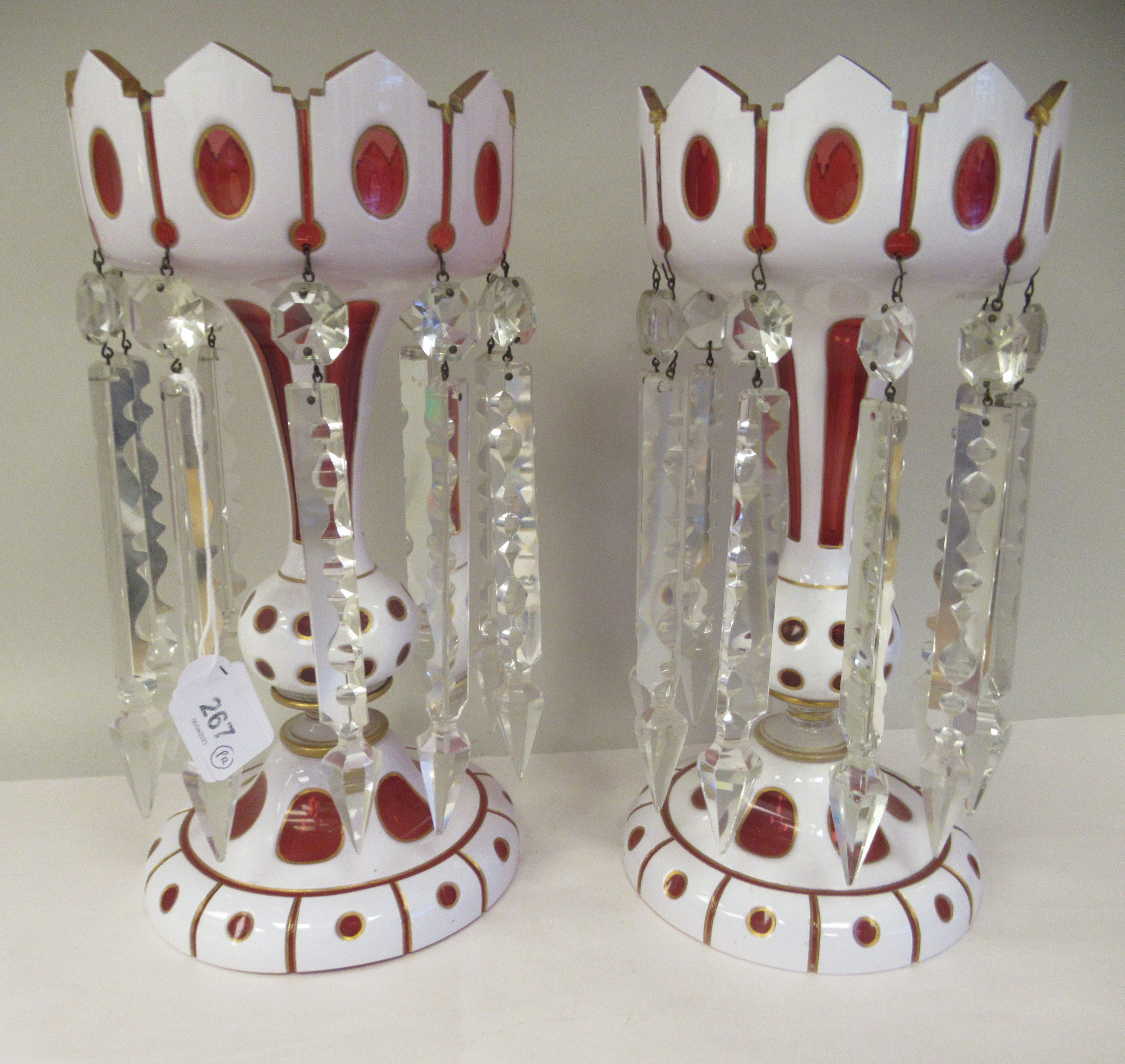 A pair of late 19thC Cranberry and cut-away, part gilded, white glass lustre vases, the bowls with