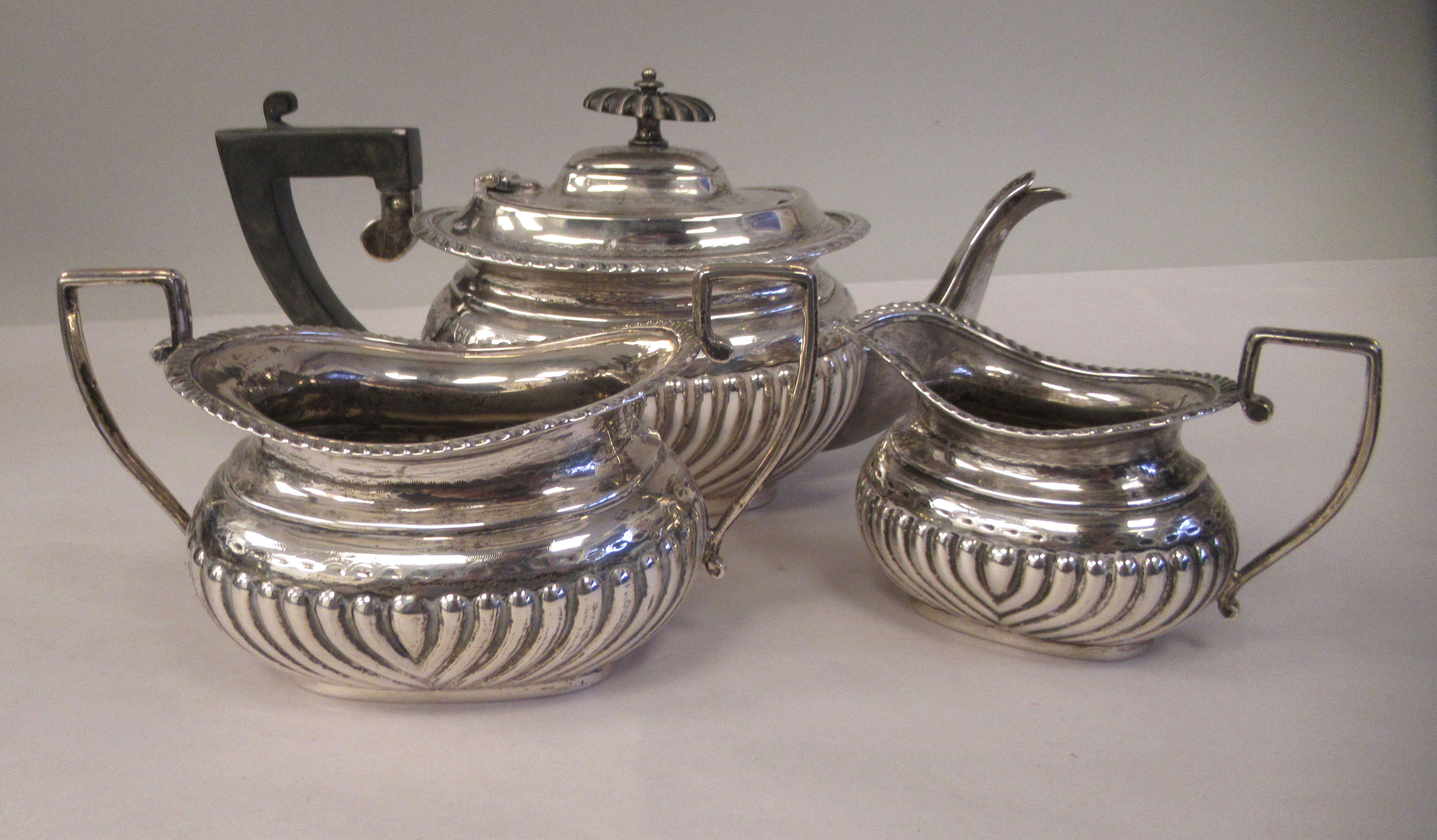 An Edwardian batchelor's three piece silver tea set of oval, ogee shape, demi-reeded form,