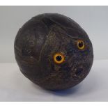 A 19thC carved coconut, in the manner of a bugbear with two inset glass eyes and a closed mouth,